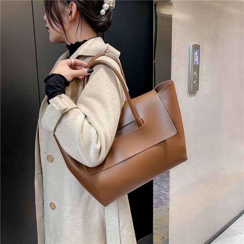 Large capacity brown shoulder bag with unique design and high-quality PU material, featuring a single strap and medium-soft hardness.