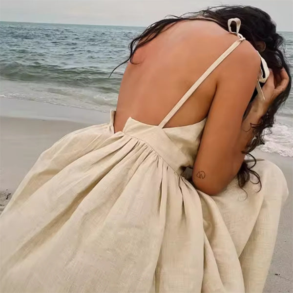 Summer V-neck dress with high waist design on beach.