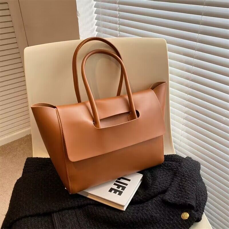 Large capacity brown shoulder bag with unique design, placed on a chair.