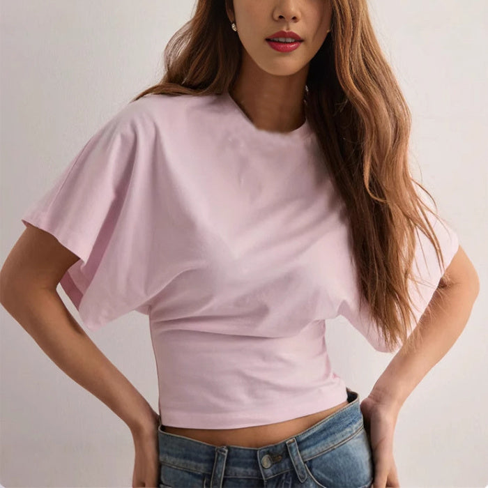 Woman wearing a light pink summer batwing sleeve T-shirt with denim jeans.