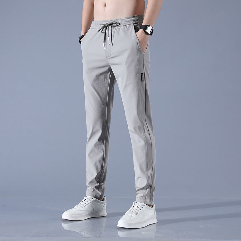 Men's plus size fashion straight pants in light gray, featuring elastic waist and drawstring, paired with white sneakers.